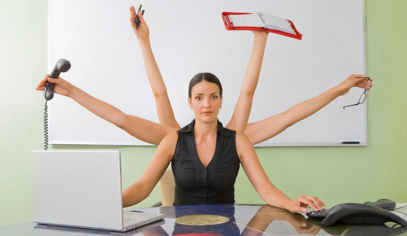 Woman sitting at a desk with 6 arms multitasking