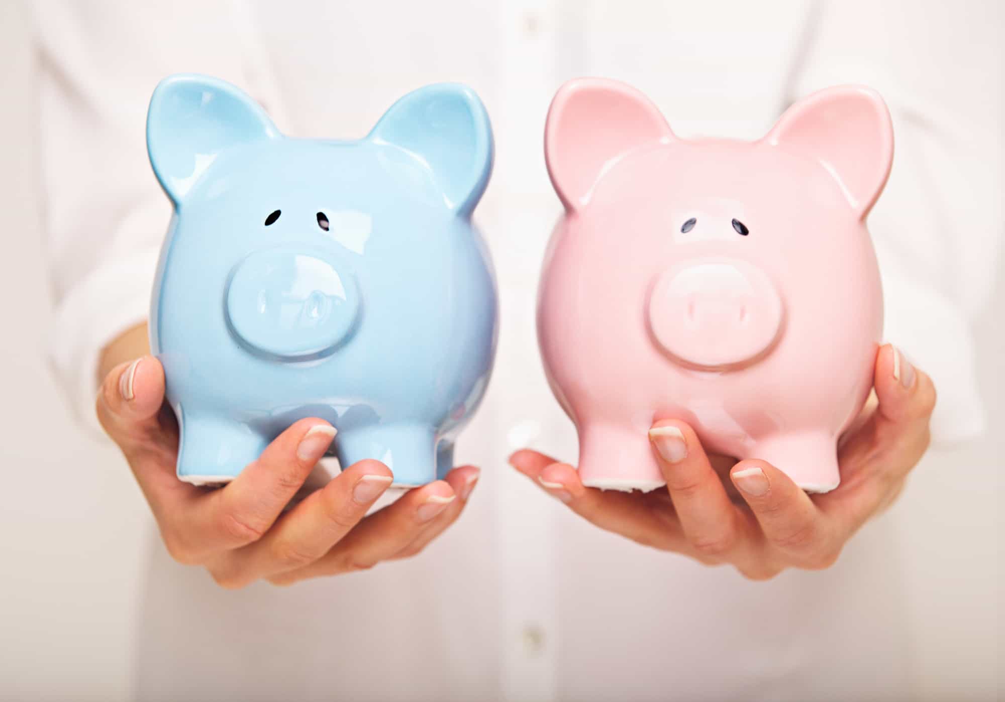 Pink ceramic piggy bank and powder blue ceramic piggy bank held in a woman's hands to separate bank accounts.